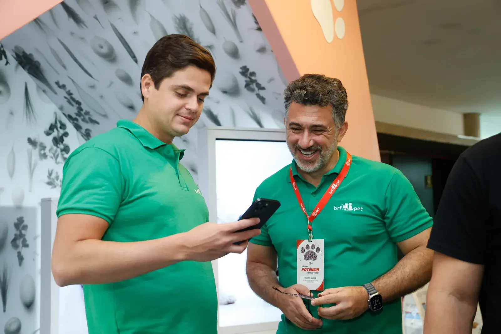 Dois participantes conferem o celular durante o credenciamento