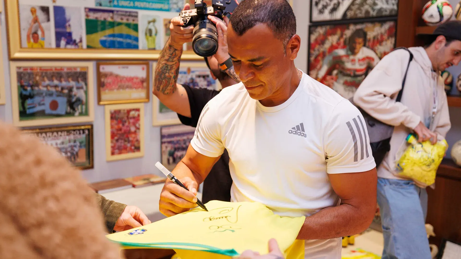 Cafu autografa uma camisa da seleção diante dos fotógrafos