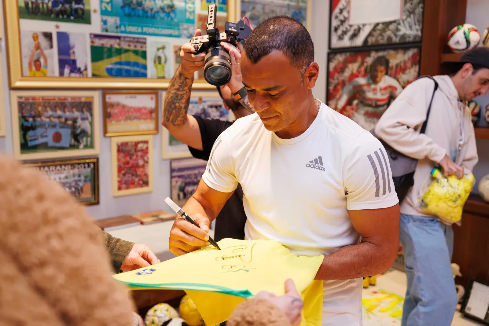 Cafu autografa uma camisa da seleção diante dos fotógrafos