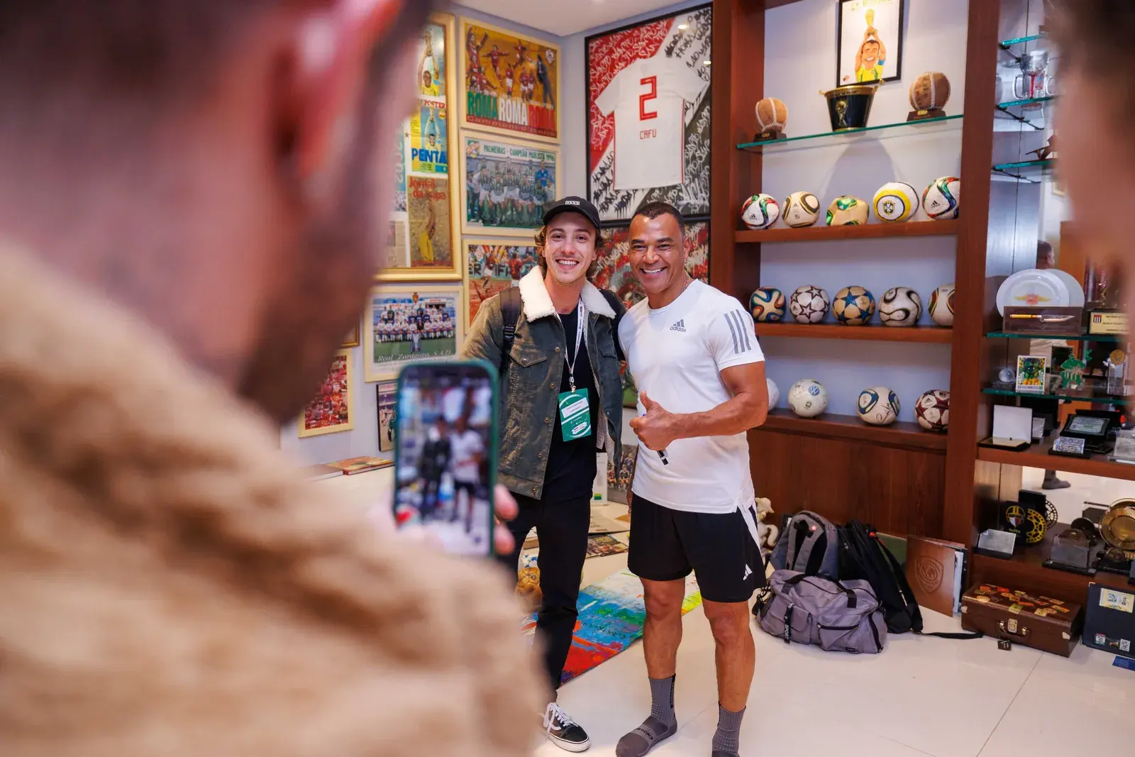 Convidada posa com Cafu na sala de troféus da casa