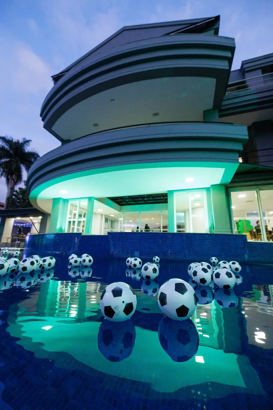 Fachada da casa do Cafu à noite, com bolas de futebol na piscina