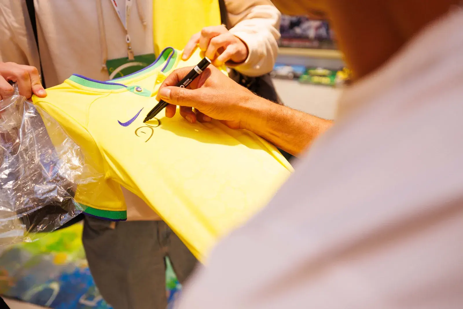 Camisa amarela sendo autografada, em close