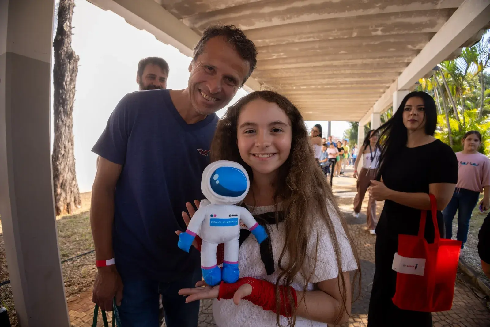 Father and daughter pose with Bosch's plush mascot, under the factory canopy