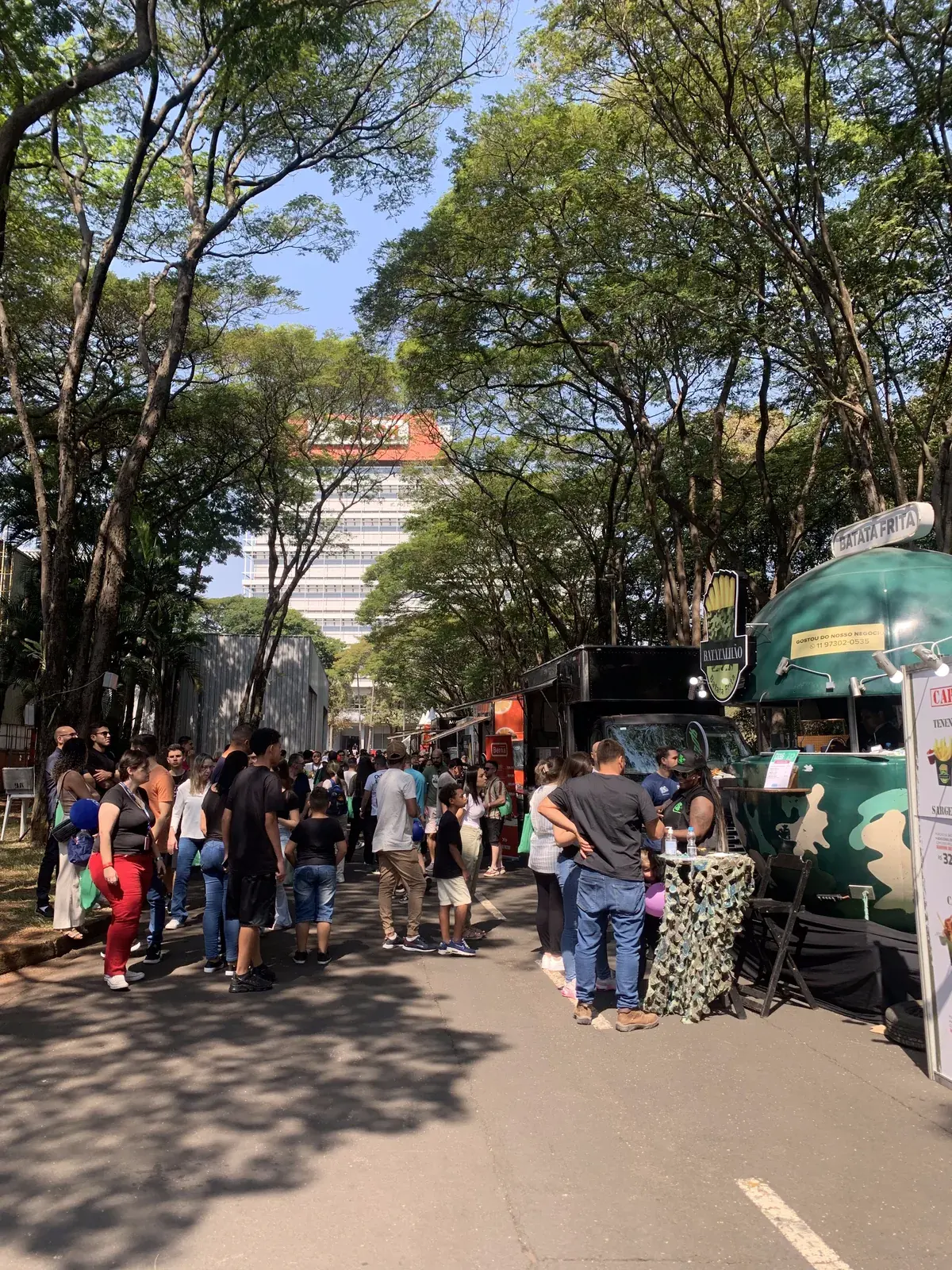 Tree-lined street at the Campinas plant with food trucks and visitors queuing